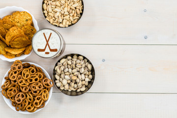 Beer with silhouettes of hockey stickson beer foam and snacks on light wooden background. Empty space for text. Top view
