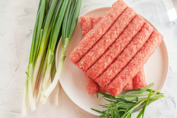 Chevapchichi is a national Balkan dish. Close up a row of fresh raw beef kebabs