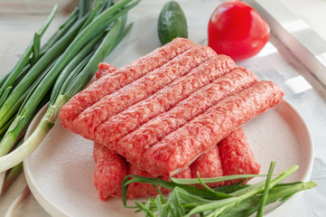 Chevapchichi is a national Balkan dish. Close up a row of fresh raw beef kebabs