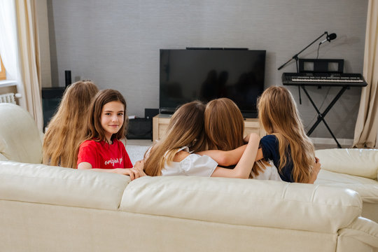 Back View Of Group Teenagers Sitting On The Sofa And Watching TV Together In Living Room