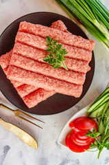 Chevapchichi is a national Balkan dish. Close up a row of fresh raw beef kebabs