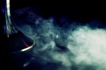 Smoking hookah, in clouds of smoke and neon light