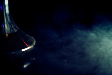 Smoking hookah, in clouds of smoke and neon light