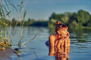 girl in the water in the lake at sunset. close up.