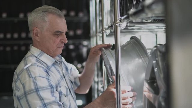 Senior man chosing new alloy wheels for his car in tires shop