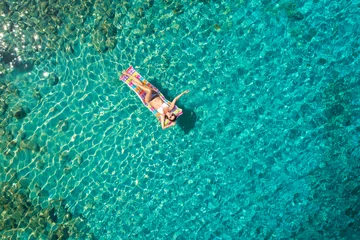 Foto op Aluminium Turquoise ocean water and relaxed swimming woman, aerial drone shot. © ZoomTeam