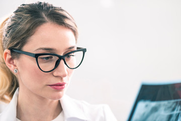 Caucasian blonde female dentist analyzing the x-ray in dental cabinet