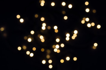 Flying golden bokeh lights in hexagon shape on black. Holiday concept