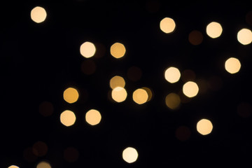Golden bokeh lights glow on black. Holiday concept