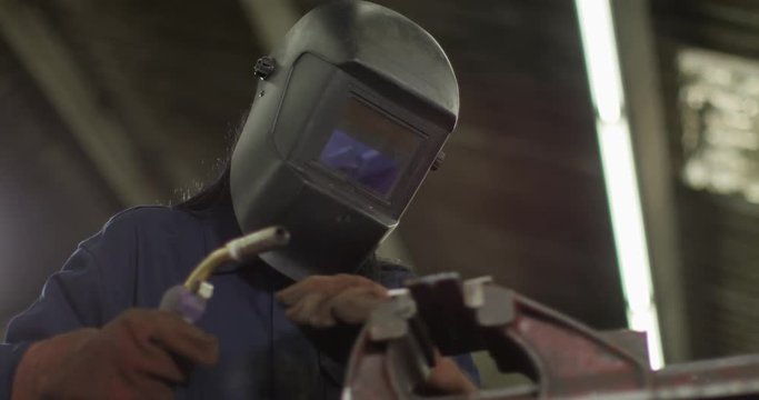 4K Female industrial worker welding steel in factory workshop. Slow motion.