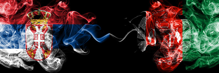 Serbia vs Afghanistan, Afghani smoky mystic flags placed side by side. Thick colored silky smokes combination of Serbian and Afghanistan, Afghani flag