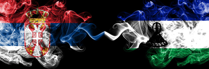 Serbia vs Lesotho smoky mystic flags placed side by side. Thick colored silky smokes combination of Serbian and Lesotho flag