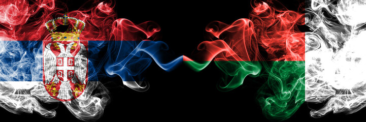 Serbia vs Madagascar, Madagascan smoky mystic flags placed side by side. Thick colored silky smokes combination of Serbian and Madagascar, Madagascan flag