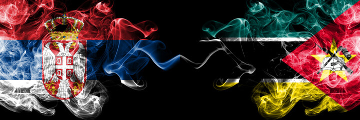 Serbia vs Mozambique, Mozambican smoky mystic flags placed side by side. Thick colored silky smokes combination of Serbian and Mozambique, Mozambican flag