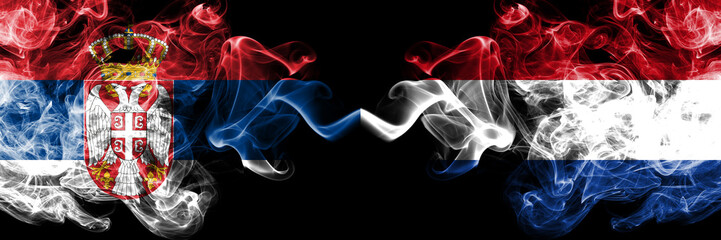 Serbia vs Netherlands, Dutch smoky mystic flags placed side by side. Thick colored silky smokes combination of Serbian and Netherlands, Dutch flag