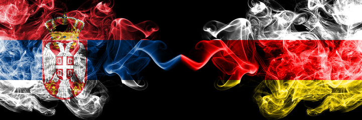 Serbia vs South Ossetia smoky mystic flags placed side by side. Thick colored silky smokes combination of Serbian and South Ossetia flag