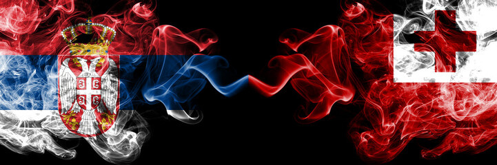 Serbia vs Tonga, Tongan smoky mystic flags placed side by side. Thick colored silky smokes combination of Serbian and Tonga, Tongan flag