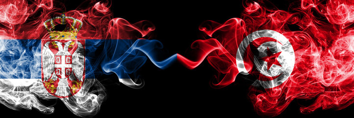 Serbia vs Tunisia, Tunisian smoky mystic flags placed side by side. Thick colored silky smokes combination of Serbian and Tunisia, Tunisian flag
