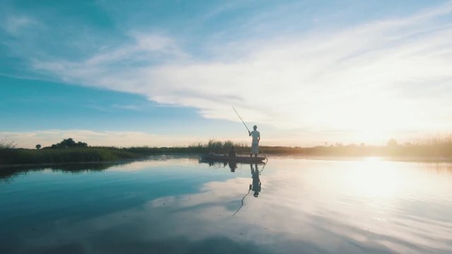 Polers Pilot Traditional Mokoro Boats At Sunrise In Botswana, Africa.