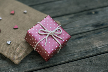 Red paper gift box tie with rope on old wooden background