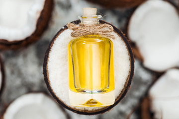 selective focus of yellow coconut oil in bottle on white coconut half