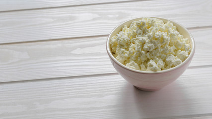 cottage cheese in a pink bowl on a light wooden table
