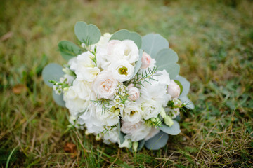 wedding bouquet of white roses lies on the grass