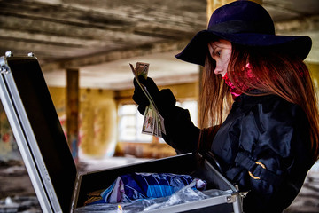 Girl in a black cloak with a diplomat and money in a ruined room. A spy in a secret meeting. Unusual photo shoot