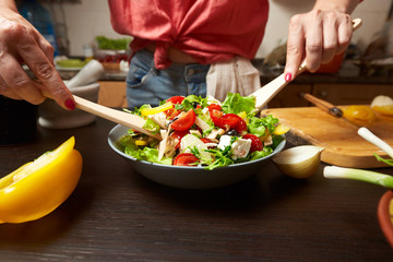 Woman hands mixing healthy greek salad