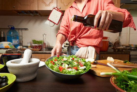 Woman Adding Olive Oil Into Healthy Greek Salad