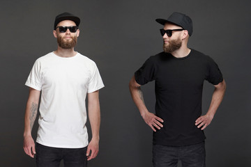 Hipster handsome male model with beard wearing white blank t-shirt and a baseball cap with space for your logo or design in casual urban style. - obrazy, fototapety, plakaty