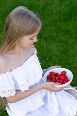 A girl with long blond hair with strawberries. Cihild eat strawberries