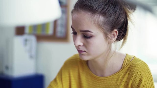 A young female student sitting at the table, studying.