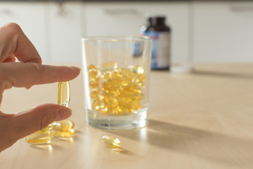 Fish oil capsules closeup in a glass jar for good health on wooden table background. Salmon fish oil in a capsule. Supplementary food. Omega 3 with Vitamin E.