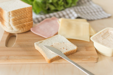Composition for making sandwich with cheese and ham on a wooden table in the bright kitchen. Lunch. Sandwich with lettuce. Healthy eating concept.