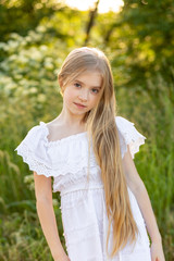 Beautiful young girl with long blond hair with a bouquet in her hands. Girl walking in the countryside