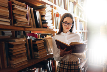 people, knowledge, education and school concept - student girl or young woman reading a book in the old library