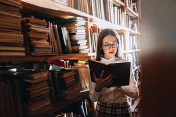 people, knowledge, education and school concept - student girl or young woman reading a book in the old library