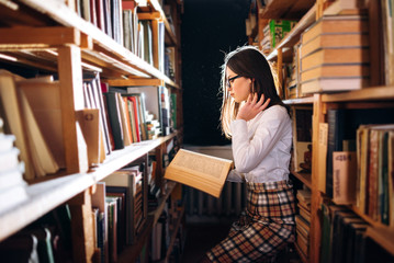 people, knowledge, education and school concept - student girl or young woman reading a book in the old library