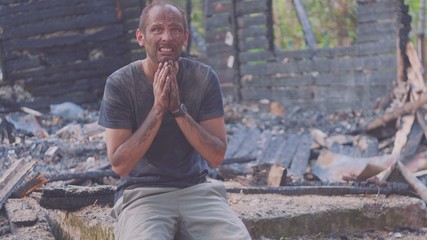 Portrait of a sad man on the background of a burned house, after fire . Consequences of fire...