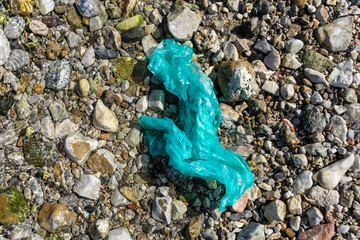 Garbage on a stony beach. Foil and plastic on the stones. Do not litter, save the planet,