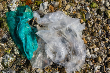 Obraz premium Garbage on a stony beach. Foil and plastic on the stones. Do not litter, save the planet,