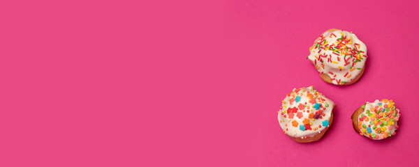 Creative flat lay food concept of sweet cake with multi-colored decoration on a pink background....