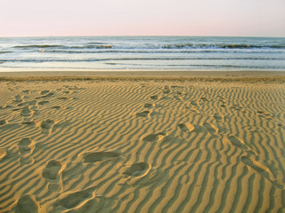 Morning empty beach and footprints on sand