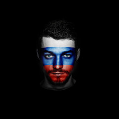 Flag of Russia painted on a face of a man on black background.
