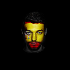 Flag of Spain painted on a face of a man on black background.