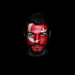 Flag of Turkey painted on a face of a man on black background.