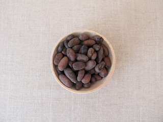 Roasted cocoa beans in a wooden bowl
