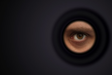 The eye of a man looking out of the eyepiece, the concept of surveillance, peeping, mystery; shot...