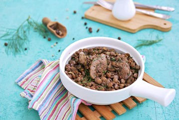 Hearty meal, fried chicken liver with boiled green lentils and spices in white ceramic pan.